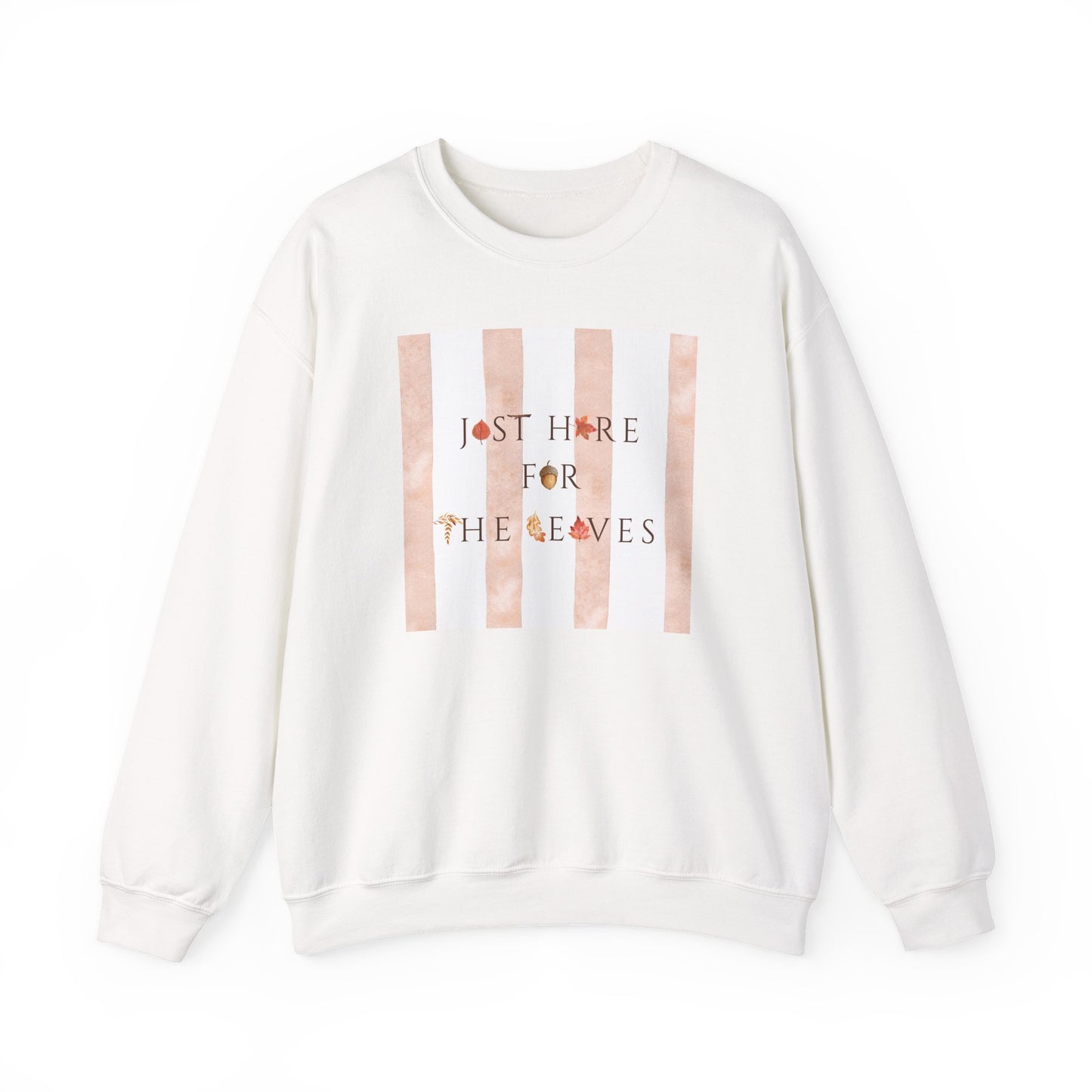 An off-white crewneck sweatshirt featuring a graphic print on the front with vertical peach stripes and the text 'JUST HERE FOR THE LEAVES' decorated with small autumn leaves.