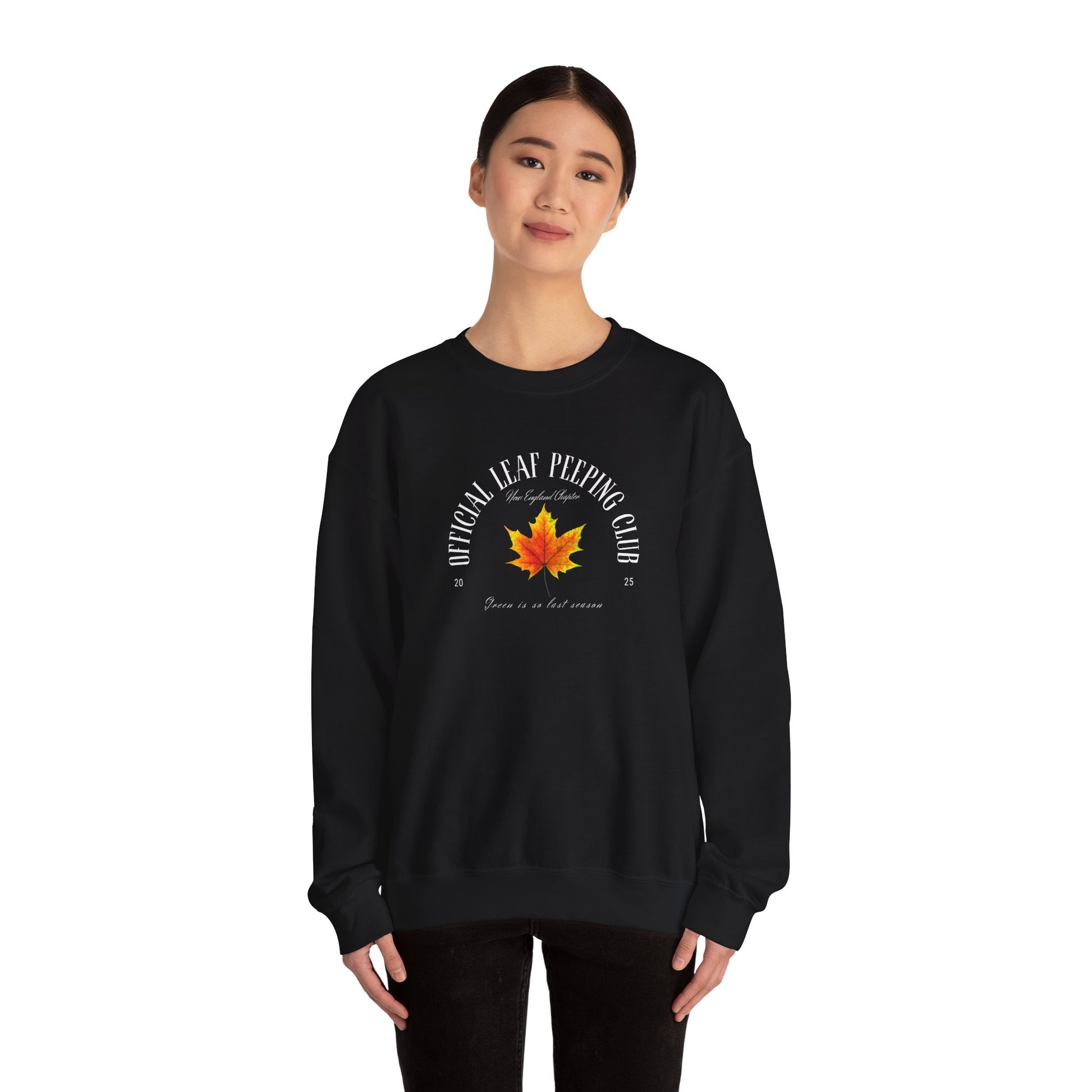 Person wearing a black sweatshirt with fall leaf and text on a white background