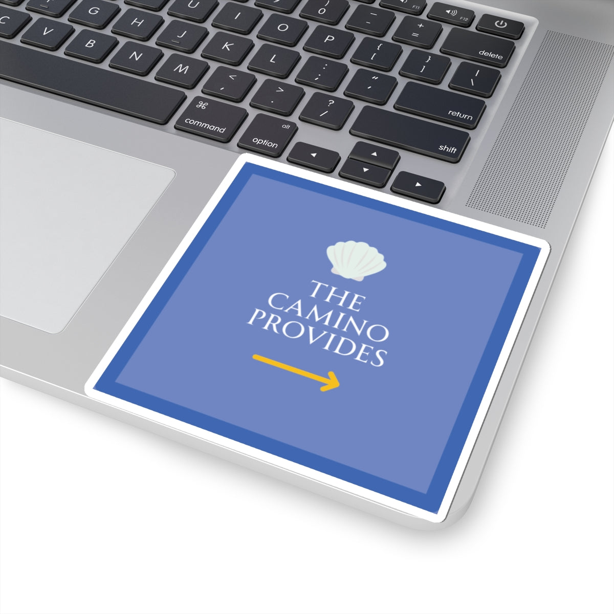 Laptop with a blue card displaying 'The Camino Provides' on the keyboard