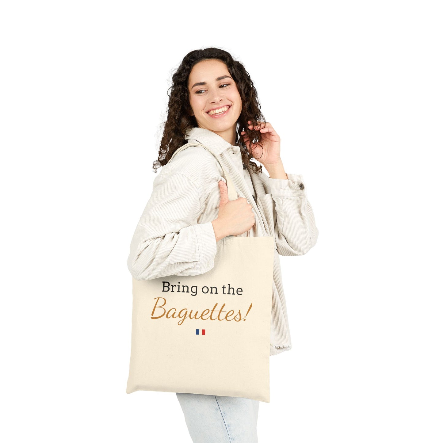 Woman holding a tote bag with a French baguette design and text on a white background