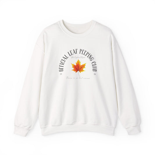 An off-white crewneck sweatshirt featuring a graphic print on the front with a red and orange maple leaf in the center, surrounded by the text 'OFFICIAL LEAF PEPPING CLUB' and 'Winter is not over yet'.
