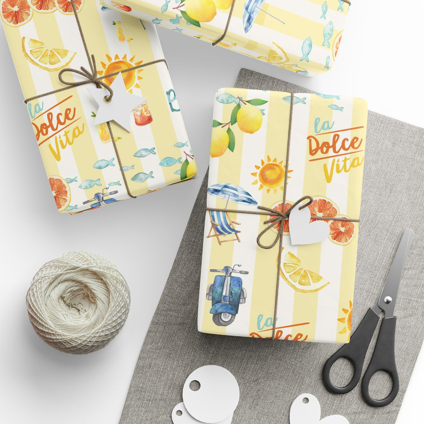 Gift wrap with 'La Dolce Vita' design, scissors, and string on a white surface