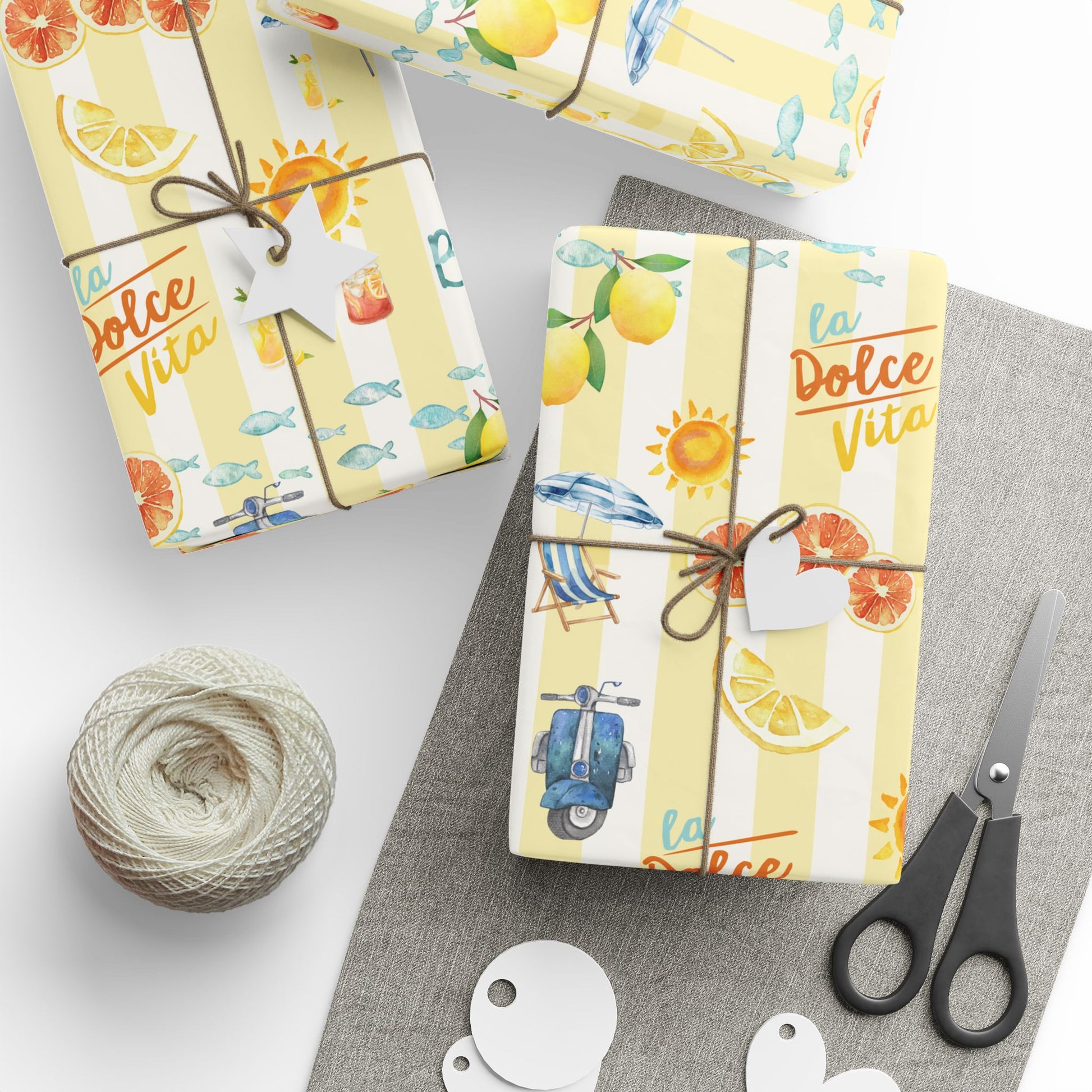 Gift wrap with 'La Dolce Vita' design, scissors, and string on a white surface