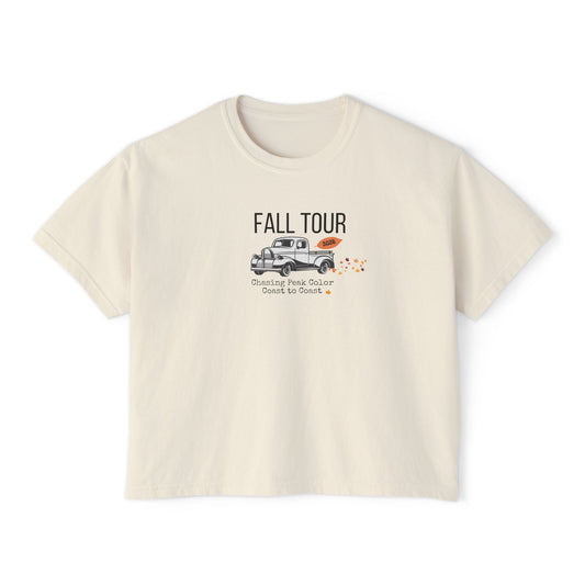 A cream-colored short-sleeve t-shirt with a graphic on the front that reads 'FALL TOUR' above an illustration of a pickup truck and small orange leaves.