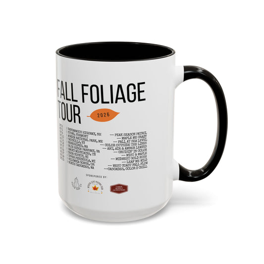 A white ceramic coffee mug with a black handle and black interior, featuring a printed black text itinerary for a 'Fall Foliage Tour 2026' with a small orange leaf graphic.
